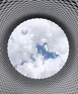 A view of the sky through a circular hole in contemporary architecture