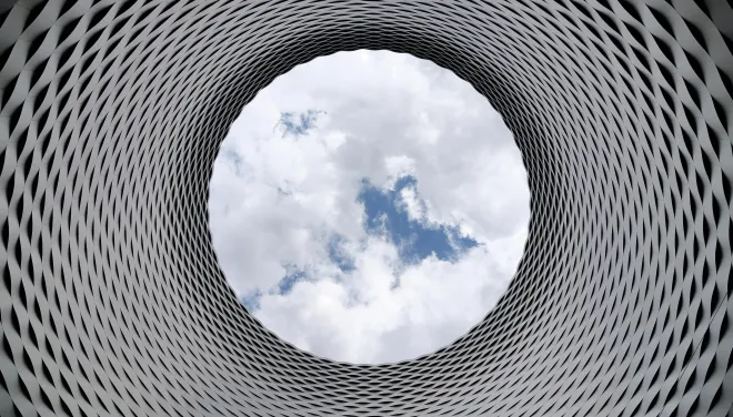 A view of the sky through a circular hole in contemporary architecture